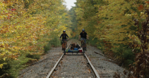 2 bicyclists riding on abandoned railroad tracks