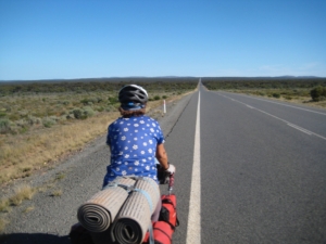 Woman riding bicycle on long empty road