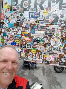Man standing in front of street signed covered in travel stickers