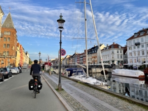 A man riding a bicycle down a street along a canal