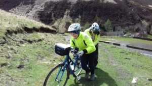 Tow women pushing loaded touring bicycles up a mountain trail