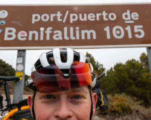 man in bicycle helmet standing in front of a road sign