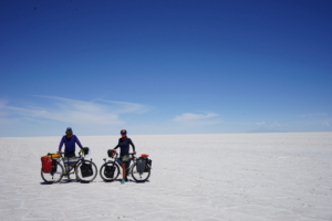 Two people posing with their loaded touring bicycles on a desert flat