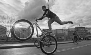 A man doing a trick while riding a bicycle by standing on the seat