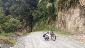 A person on an empty road working on a broken bicycle