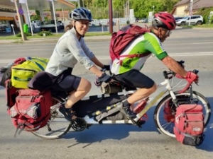 Man and woman riding a loaded tandem touring bicycle
